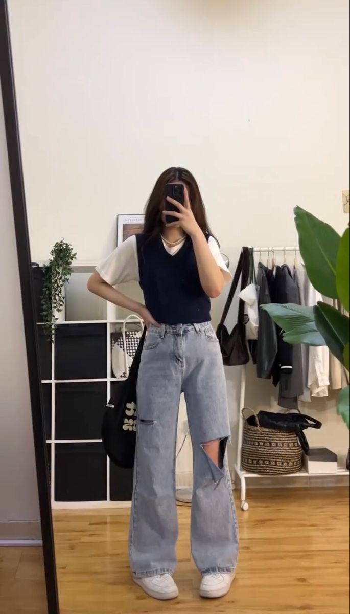 Kaos polos putih dipadukan dengan sweater vest dan rok atau celana